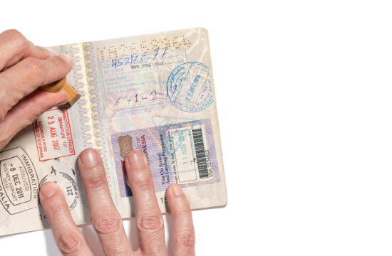 Stamping visa on passport pages with a lot of visa stamps.